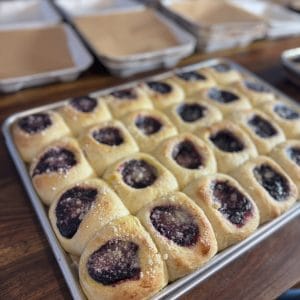 berry kolaches in a half sheet pan on a wood table